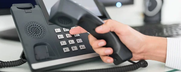 homem digitando número no Telefone VoIP