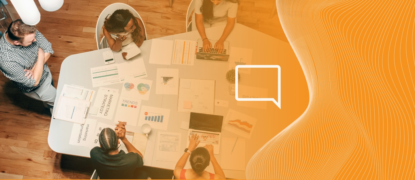 Pessoas trabalhando sentadas, discutindo sobre integrar VoIP com CRM e ERP na empresa.