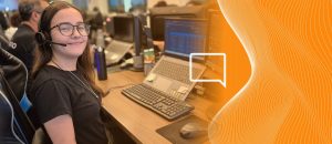 Pessoa de Headset tralhando com atendimento humanizado online em uma mesa com 2 computadores