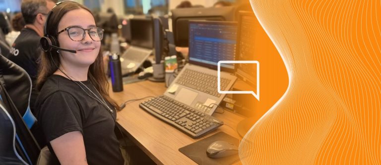 Pessoa de Headset tralhando com atendimento humanizado online em uma mesa com 2 computadores