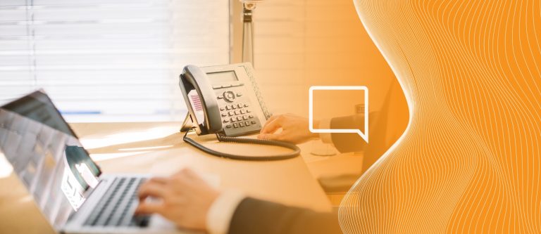 Pessoa tirando a mão de um telefone fixo e com as mãos em um laptop. Simbolizando essa movimentação que empresas deveriam fazer se afastando de tecnologias ultrapassadas como telefonia fixa tradicional e se aproximando do futuro, representado pelo VoIP no computador.